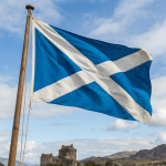 The national flag of Scotland flying from a wooden flagpole.